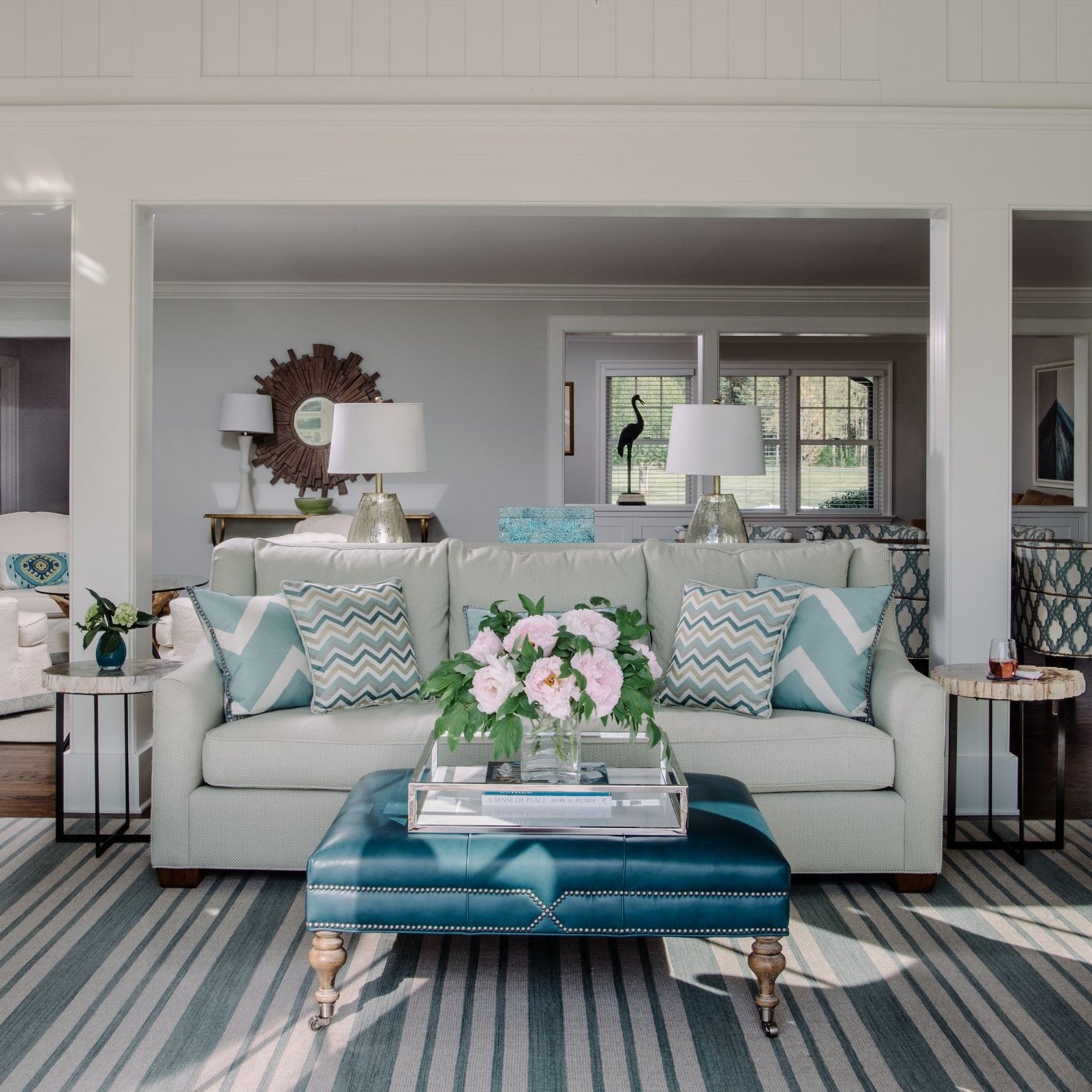 Sunroom with light blue accents and blue leather coffee table and striped rug - interior design by Jamie Merida Interiors