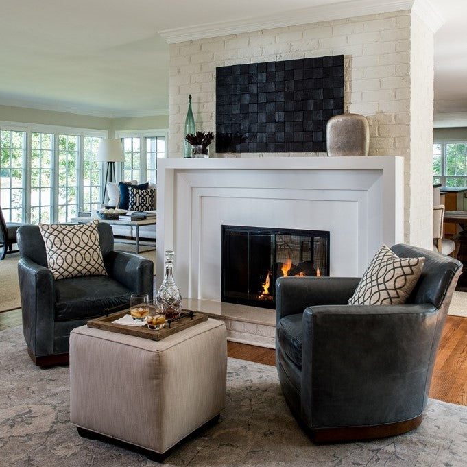 Masculine interior design by Jamie Merida - shows fireplace with two club chairs and crystal decanter