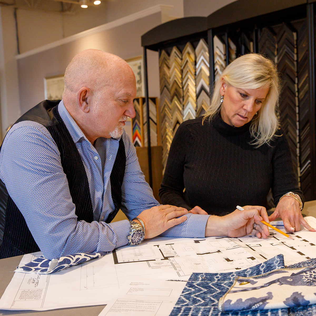 Jamie Merida and lead interior designer Denise Perkins looking at a floor plan and working on a client project