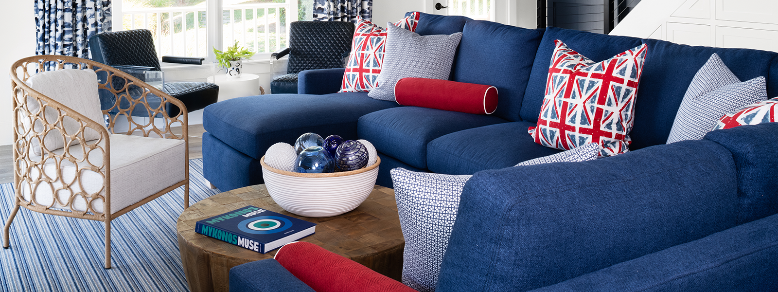 Close up of living room with blue sectional with union jack pillows and wicker side chair - Jamie Merida Interiors
